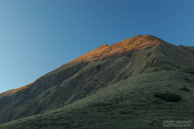 Sonnenaufgang auf einem grünen Berghang