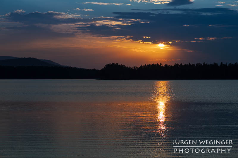 Sonnenuntergang über dem schwedischen See: Die Sonne taucht den Himmel in warme Farben und spiegelt sich auf der ruhigen Wasseroberfläche. #Schweden #Naturfotografie #Sonnenuntergang #See #Wald