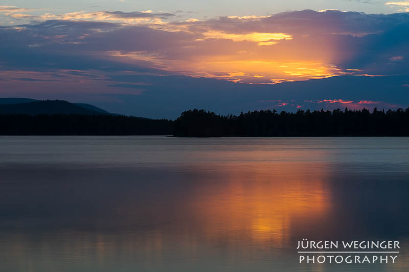 Sonnenuntergang über dem schwedischen See: Die Sonne taucht den Himmel in warme Farben und spiegelt sich auf der ruhigen Wasseroberfläche. #Schweden #Naturfotografie #Sonnenuntergang #See #Wald