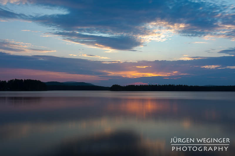 Sonnenuntergang über dem schwedischen See: Die Sonne taucht den Himmel in warme Farben und spiegelt sich auf der ruhigen Wasseroberfläche. #Schweden #Naturfotografie #Sonnenuntergang #See #Wald