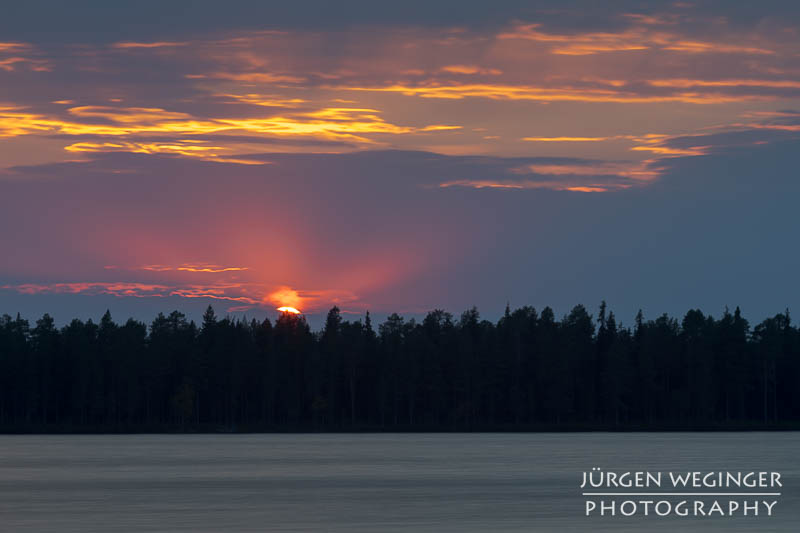 Sonnenuntergang über dem schwedischen See: Die Sonne taucht den Himmel in warme Farben und spiegelt sich auf der ruhigen Wasseroberfläche. #Schweden #Naturfotografie #Sonnenuntergang #See #Wald